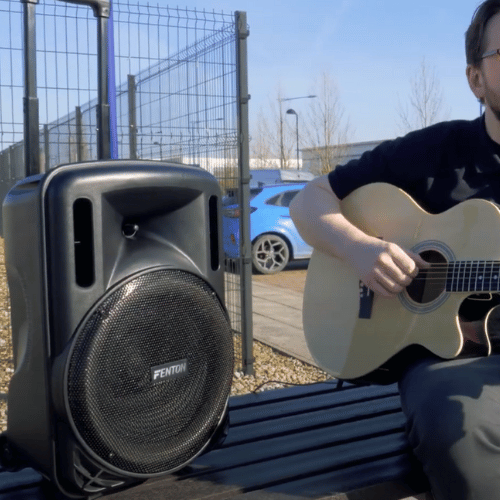 Fenton FT12LED MK2 12" Portable PA System with guitar being played through the speaker in an outdoor location